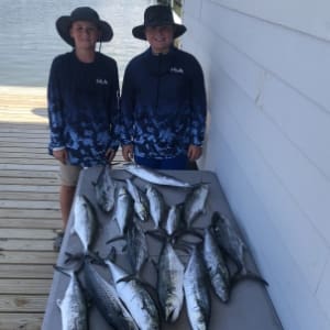a couple shows off their fishing catch on a tarp