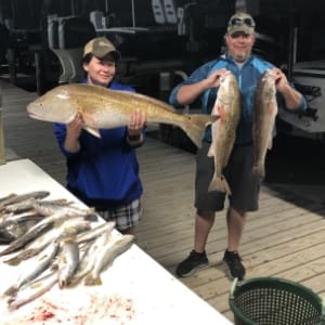 Man and boy show off large fishing charter catch